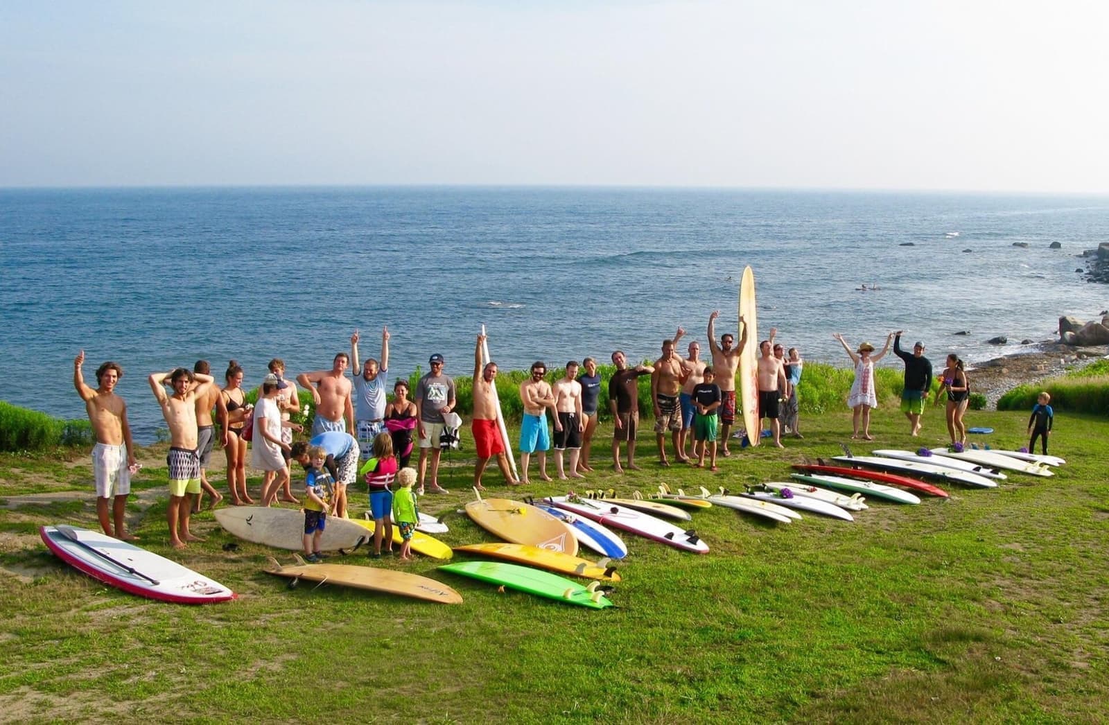 Group photo with surfboards lined up, ocean behind